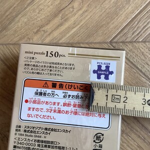 May include: A mini puzzle box with the text "mini puzzle 150 pcs." and Japanese text. A ruler is placed next to the box. The box has a sticker that says "PCS.SIZE SAMPLE".