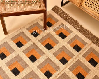 May include: A rectangular area rug featuring a repeating geometric pattern of nested squares in shades of orange, gray, and black on a cream background. The rug has a textured weave and short fringe along the edge, with the text RUGSEXPORTS visible.
