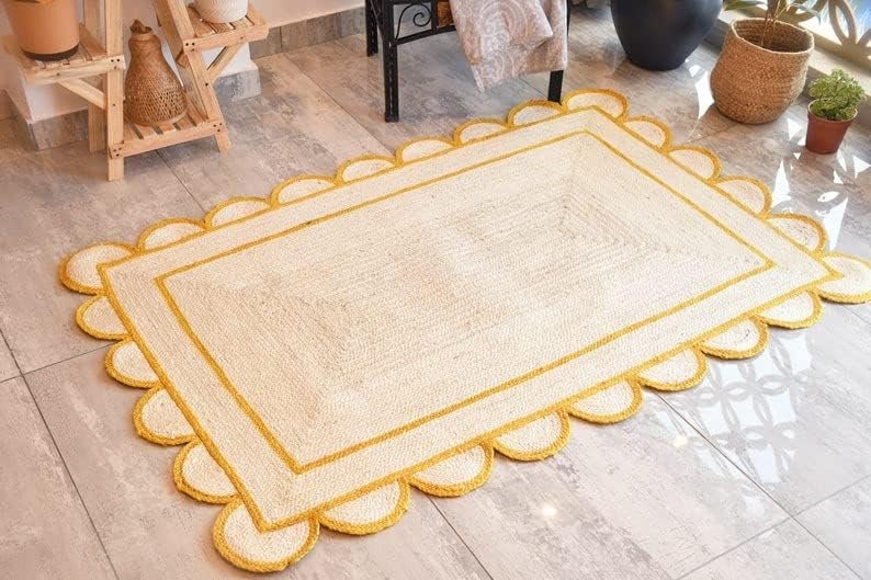 May include: A white and yellow jute rug with a scalloped edge. The rug has a double yellow border.