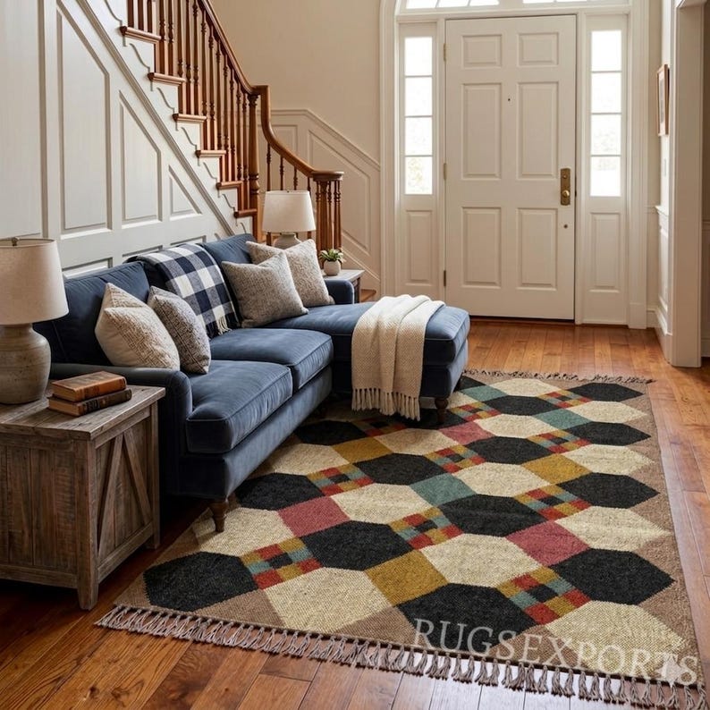 Pu&ograve; includere: Soggiorno con divano blu, cuscini e coperta con frange. Un tappeto geometrico con forme nere, beige, rosse e gialle &egrave; sul pavimento in legno. Tavolini in legno e lampade completano l'atmosfera calda. Il tappeto misura circa 244 cm x 305 cm.