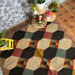 Pu&ograve; includere: Tappeto a motivi geometrici con un motivo esagonale ripetuto in nero, beige, rosso e verde acqua. Il tappeto ha un bordo sfrangiato ed &egrave; posto su un pavimento in legno. Vasi di fiori decorativi su supporti in legno.