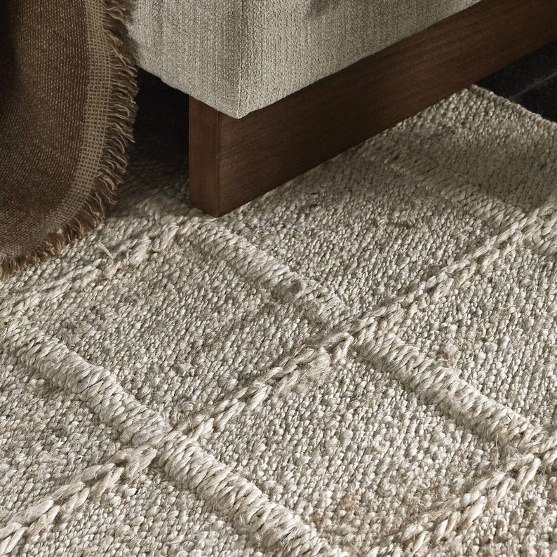 May include: A light gray woven rug with a textured, braided design. The rug has a subtle pattern of horizontal stripes.