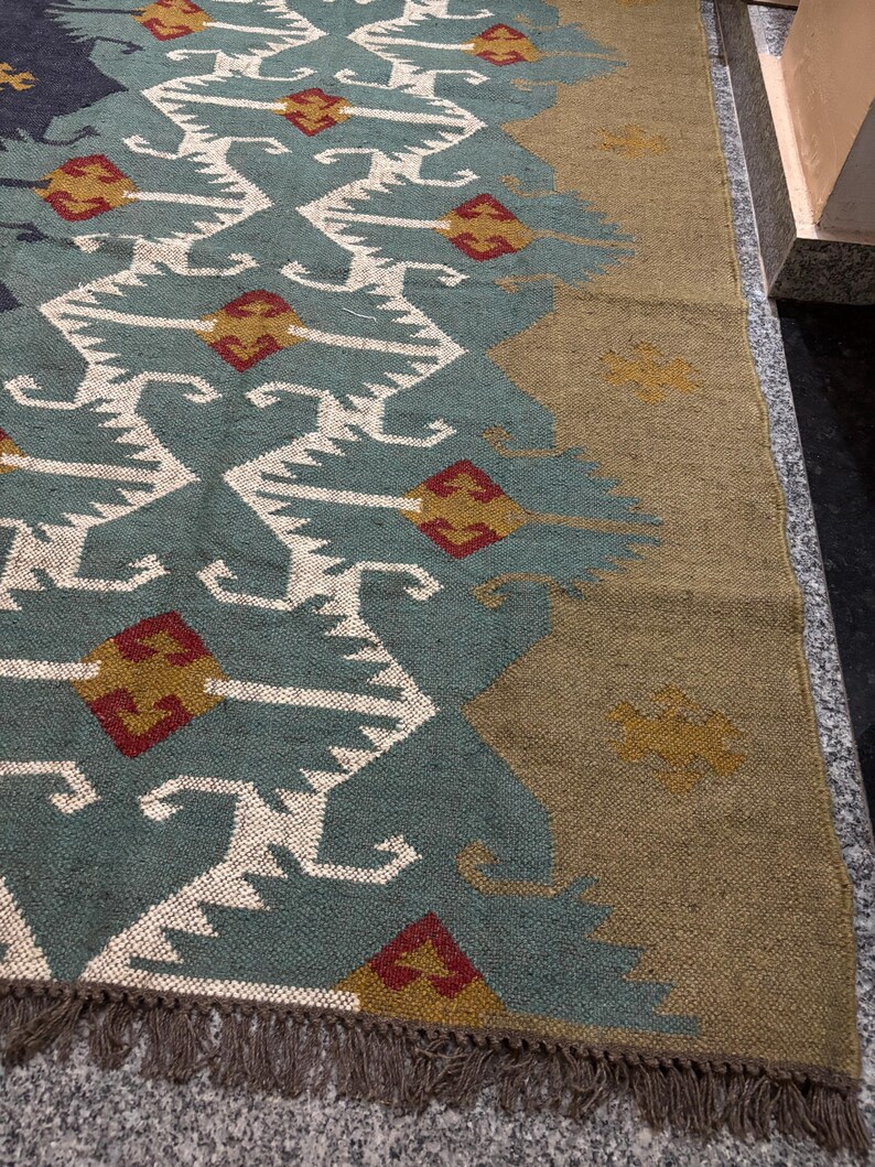 May include: A teal and brown patterned rug with a geometric design. The rug has a fringe border and is made of woven fibers.