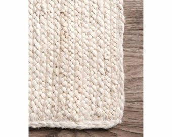 May include: A rectangular area rug featuring a thick, chunky braided weave made from natural off-white fibers. The rug has a dense, textured surface with a consistent pattern of interlocking loops that create a heavy, durable appearance.