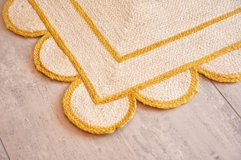 May include: A white and yellow jute rug with a scalloped edge. The rug has a double yellow border.