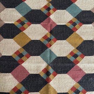 Pu&ograve; includere: Tappeto tessuto con motivo geometrico di forme interconnesse in blu navy, crema, oro, verde acqua, rosso e rosa. Il design del tappeto presenta un motivo ripetitivo di ottagoni e diamanti.