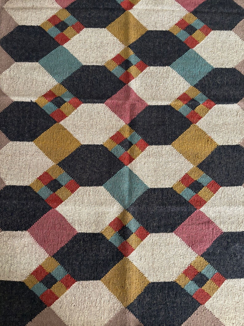 Pu&ograve; includere: Tappeto tessuto con motivo geometrico di forme interconnesse in blu navy, crema, oro, verde acqua, rosso e rosa. Il design del tappeto presenta un motivo ripetitivo di ottagoni e diamanti.