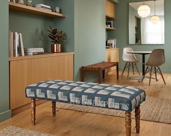 May include: A rectangular upholstered bench featuring a geometric pattern in shades of blue, grey, and cream. The bench is supported by four turned wooden legs with a dark brown finish. The text RUGSEXPORTS is visible on the seat surface.