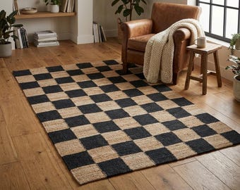 May include: A rectangular area rug featuring a repeating checkerboard pattern of alternating natural tan and black squares. The rug is constructed with a textured, woven fiber material and lies flat on a light brown wooden floor surface.