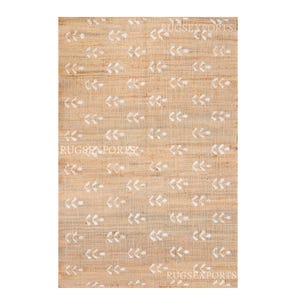 May include: A natural fiber rug with a beige background and a white leaf pattern. The rug has a subtle texture and a simple design.