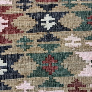 Puede incluir: Primer plano de un textil tejido con un patr&oacute;n geom&eacute;trico. El dise&ntilde;o presenta formas repetidas de diamantes y cruces en tonos beige, azul marino, rojo, verde y rosa. El texto "RUGS EXPORTS" es visible en la parte inferior.