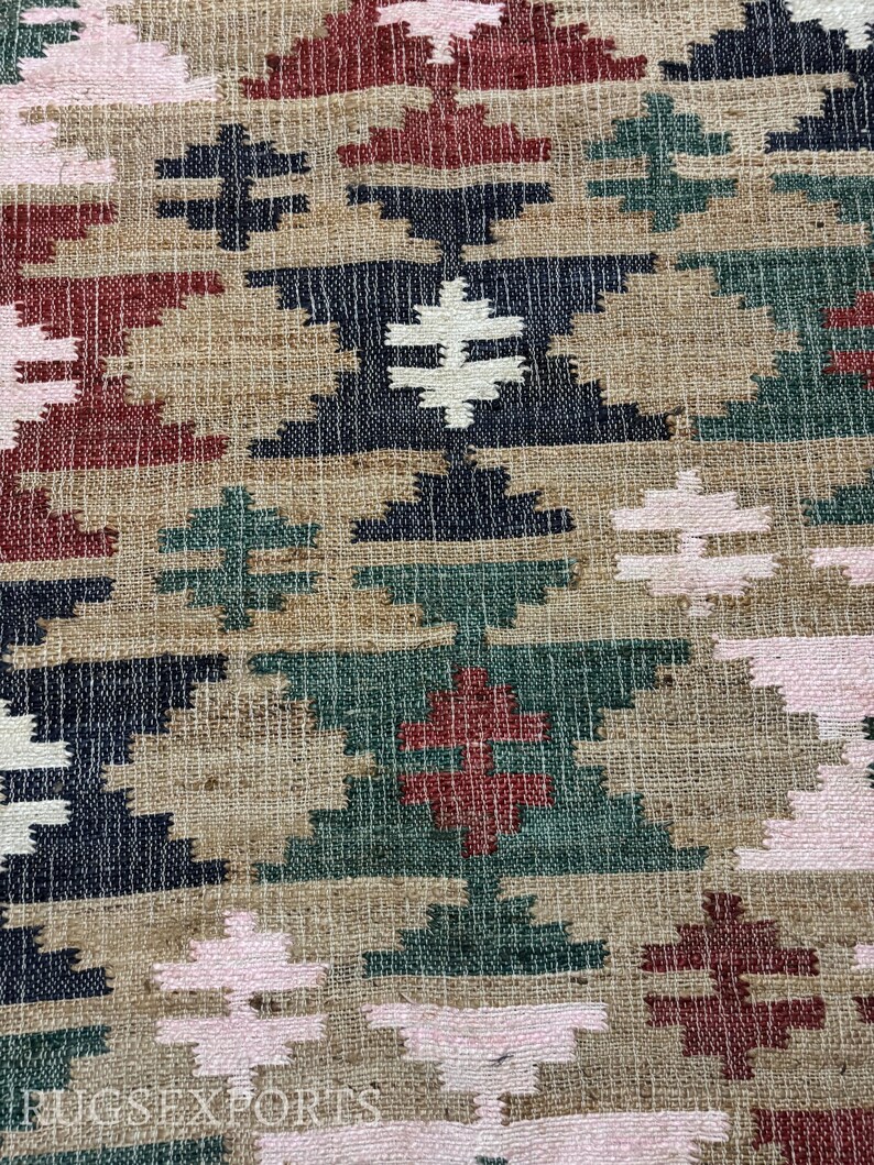 Puede incluir: Primer plano de un textil tejido con un patr&oacute;n geom&eacute;trico. El dise&ntilde;o presenta formas repetidas de diamantes y cruces en tonos beige, azul marino, rojo, verde y rosa. El texto "RUGS EXPORTS" es visible en la parte inferior.