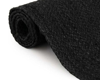 May include: A rolled-up, black woven jute rug. The rug is made of thick, braided fibers, creating a textured surface. The dark color and natural material suggest a rustic or bohemian style, suitable for home decor.