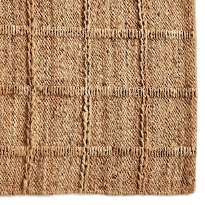 May include: A natural fiber rug with a woven, textured pattern in a light brown color.