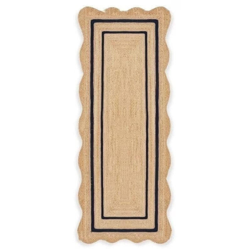 May include: A rectangular jute rug with a scalloped edge. The rug has a natural tan color with a black border and a rectangular design in the center. This rug is suitable for a hallway or entryway.
