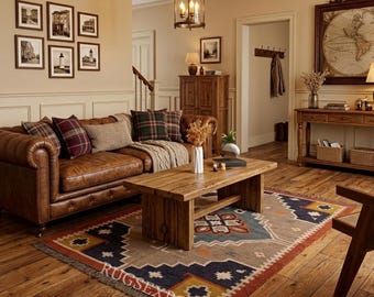 May include: A cozy living room scene featuring a brown leather sofa with plaid pillows, a wooden coffee table, and a patterned rug. The room is decorated with framed pictures and a hanging light fixture.