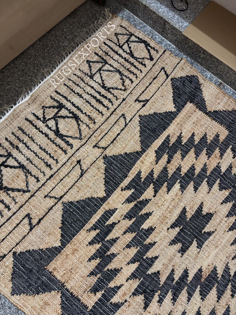 May include: A brown and black jute rug with a geometric pattern. The rug has a fringed edge and is made of natural fibers.