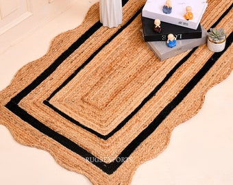 May include: A natural fiber rug with a scalloped edge and black trim. The rug is made of jute and has a natural, earthy color. The rug is perfect for adding a touch of rustic charm to any room.