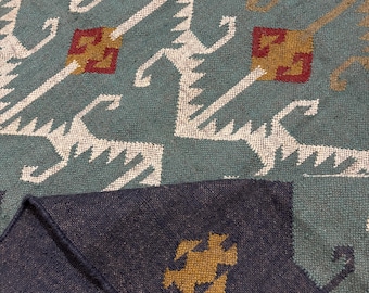 May include: A close-up of a blue and brown patterned rug with a geometric design. The rug has a fringe border and is made of a soft, woven material.