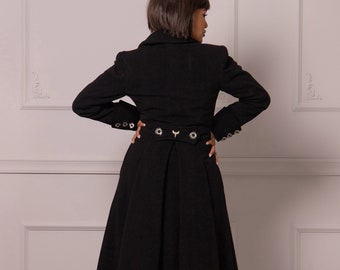 May include: A long black coat with a high collar and a fitted waist. The coat has a flared skirt and is decorated with silver buttons.