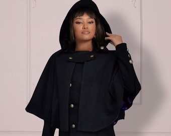 May include: A black hooded cape with gold buttons and a purple lining. The cape is worn over a black long skirt.