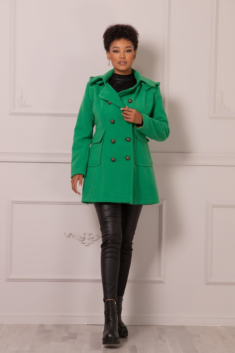 May include: A green double-breasted peacoat with a hood. The coat has four large buttons and two pockets.