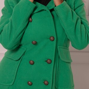 May include: A green hooded double-breasted coat with six large brown buttons.