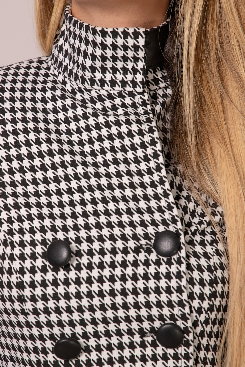May include: Black and white houndstooth pattern jacket with a high collar and black buttons.