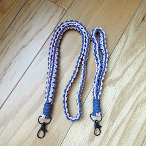 May include: A gray and pink braided lanyard with two black metal swivel clips.
