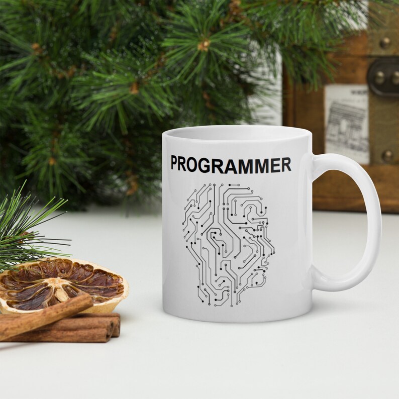 Op de afbeelding: Witte keramische mok met een zwart printje van een printplaat en het woord "PROGRAMMEUR" in het zwart bovenaan.