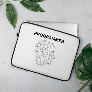May include: White laptop sleeve with black edging, displaying the word "PROGRAMMER" in black. A circuit board design, shaped like a head, is below the text. The sleeve is designed to protect a laptop.