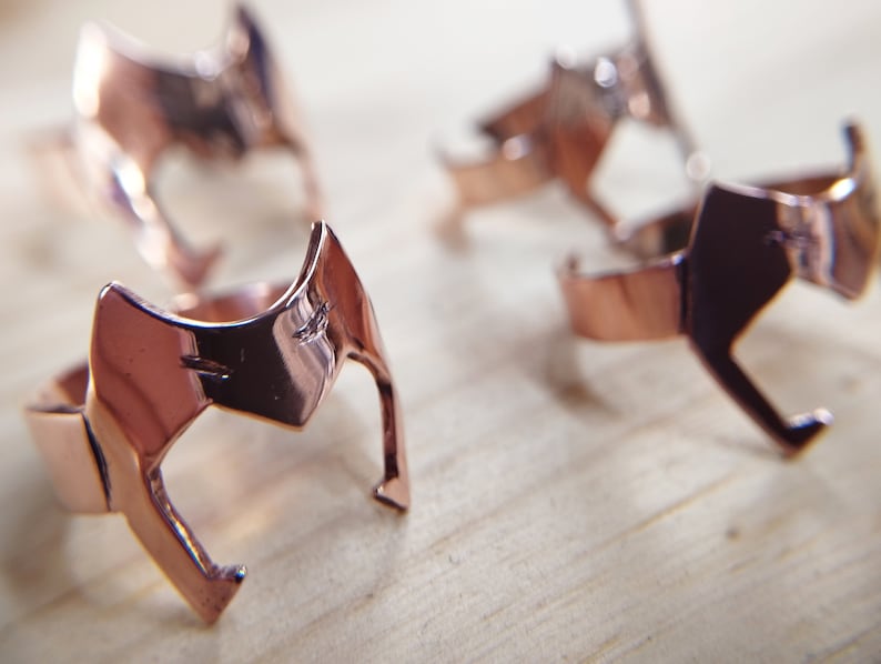 Peut inclure: Quatre bagues en or rose avec un design g&eacute;om&eacute;trique. Les bagues sont empil&eacute;es sur une surface en bois.