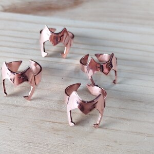 Peut inclure: Quatre bagues en or rose avec un motif de couronne. Les bagues sont dispos&eacute;es en demi-cercle sur une surface en bois.