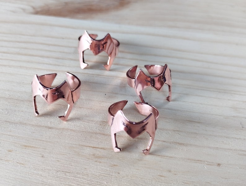 Peut inclure: Quatre bagues en or rose avec un motif de couronne. Les bagues sont dispos&eacute;es en demi-cercle sur une surface en bois.