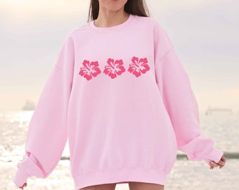 May include: A pink sweatshirt with three pink hibiscus flowers printed on the front.