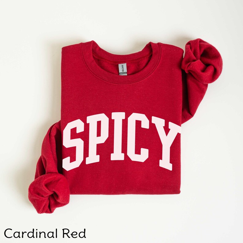 May include: Cardinal red sweatshirt with the word "SPICY" printed in pink on the front.