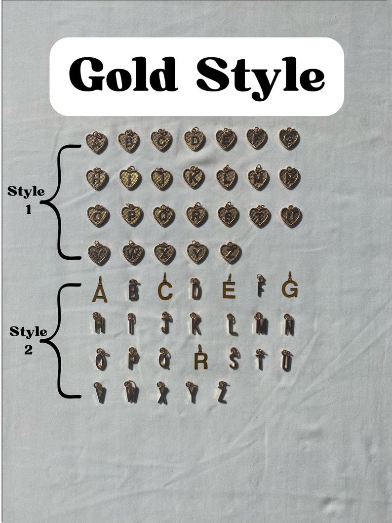 Pu&ograve; includere: Ciondoli color oro in due stili. Lo stile 1 presenta ciondoli a forma di cuore con le lettere A-Z. Lo stile 2 include singole lettere d'oro A-Z. Il testo "Gold Style" &egrave; in alto.