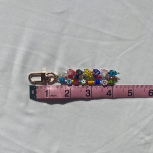 Pu&ograve; includere: Un portachiavi di perline con chiusura color oro. Il portachiavi &egrave; decorato con perline colorate, tra cui perline a forma di cuore e di fiore. Il portachiavi misura circa 10 cm di lunghezza.