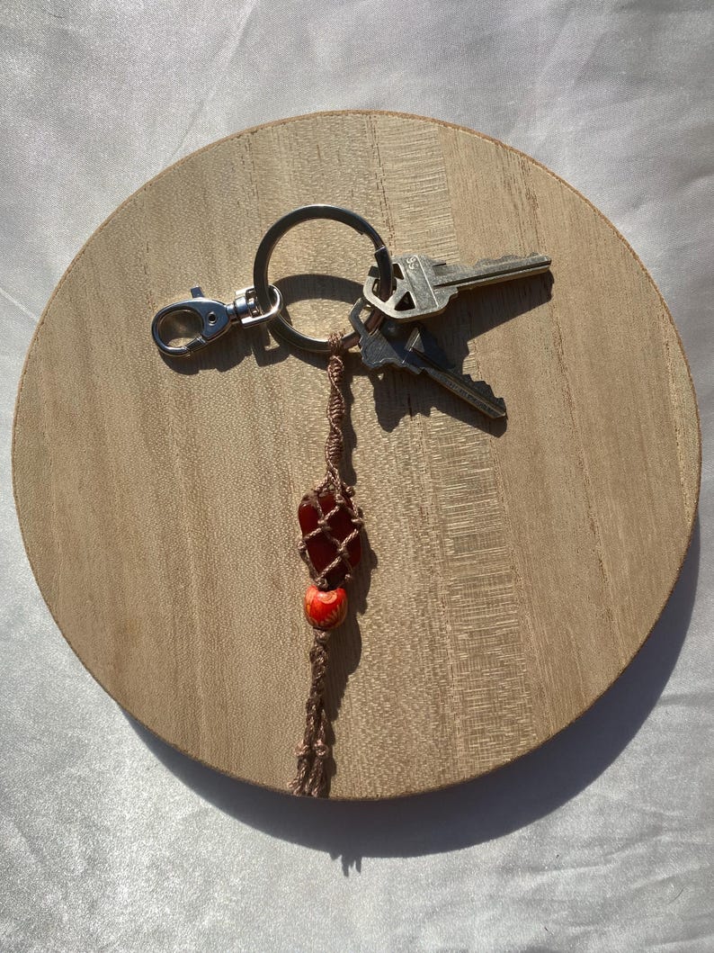 May include: A brown and red beaded keychain with a red stone charm and a silver key ring with three keys attached.