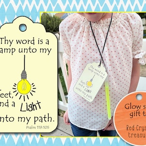 May include: A rectangular cream-coloured tag with a hole at the top, featuring a yellow lightbulb illustration and the black text: Thy word is a lamp unto my feet, and a Light unto my path. Psalm 119:105. A neon green glow stick is attached to the tag.