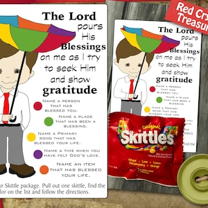 May include: Two illustrated cards with a cartoon boy holding a rainbow umbrella. Text on the cards reads "The Lord pours His Blessings on me as I try to seek Him and show gratitude." A Skittles package and a green button are also visible.