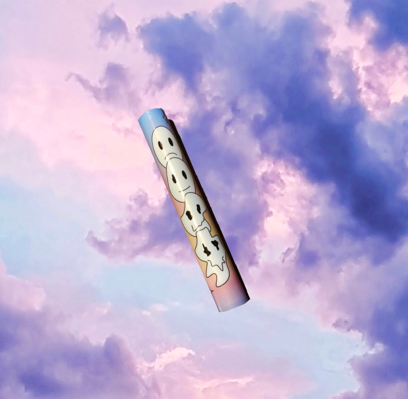 May include: Rolled poster with a repeating design of white ghost-like faces with various expressions. The poster has a gradient background of pastel colors and is set against a cloudy sky.