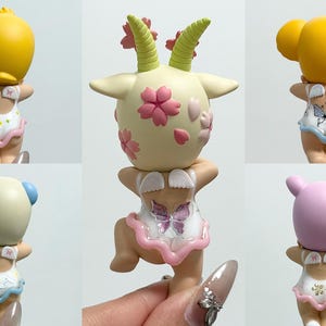 May include: A selection of small figurines, each with a different animal head on a swimsuit-clad figure. The heads are yellow, cream, and pink, with details like horns and ears. The swimsuits feature butterfly and floral patterns.