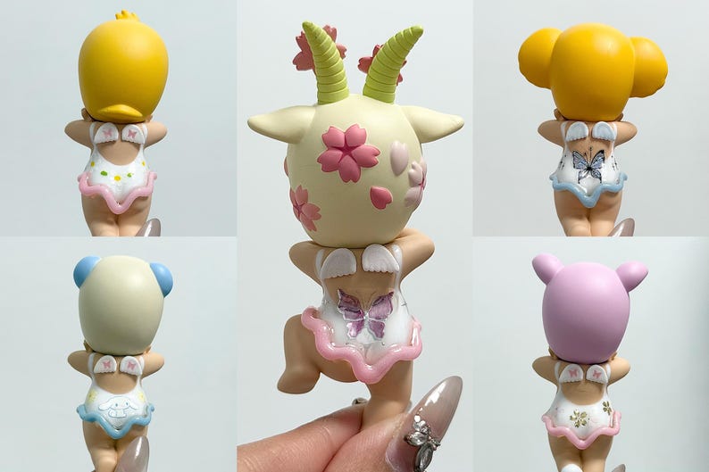 May include: A selection of small figurines, each with a different animal head on a swimsuit-clad figure. The heads are yellow, cream, and pink, with details like horns and ears. The swimsuits feature butterfly and floral patterns.