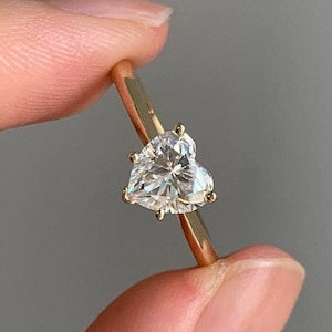 May include: A gold ring with a heart-shaped diamond.