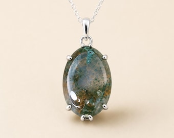 May include: A silver pendant necklace featuring an oval-shaped moss agate gemstone with green and brown inclusions. The stone is held in a six-prong setting and hangs from a delicate silver chain, showcasing a smooth, polished surface finish.