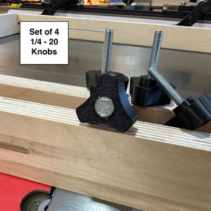 May include: Set of four black 1/4-20 knobs with threaded stems. The knobs are attached to a wooden surface.