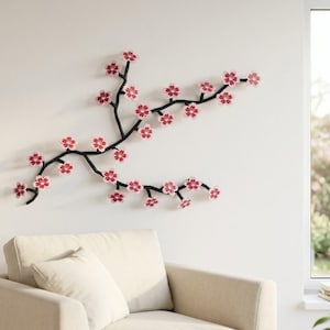 Op de afbeelding: Een wandsculptuur met een zwarte tak voorzien van meerdere roze en witte kersenbloesems. De tak strekt zich horizontaal uit over de muur en toont een gedetailleerd arrangement van bloeiende florale elementen.