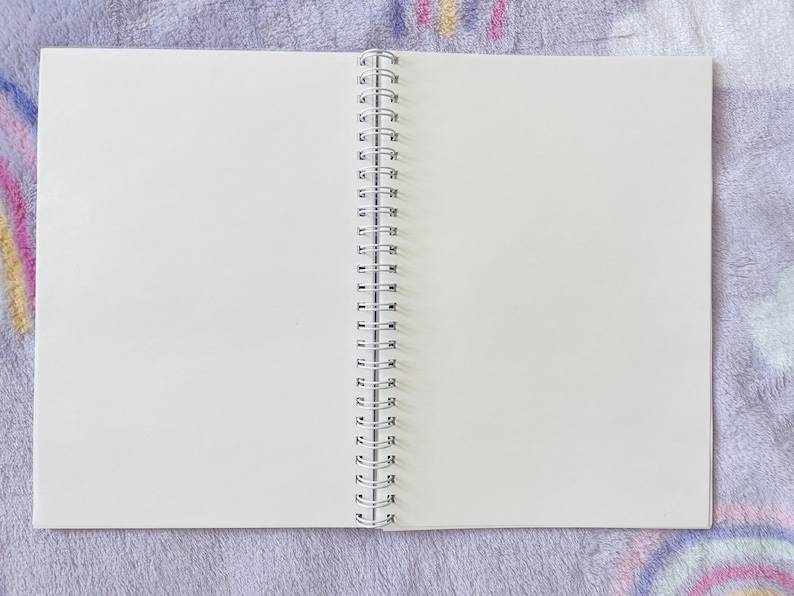 May include: A white spiral bound notebook with blank pages, open to a fresh page.