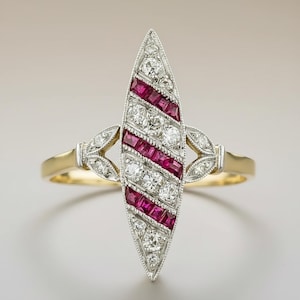 May include: A vintage ring with a gold band and a central, elongated design. The design features alternating rows of round diamonds and square-cut rubies, set in a silver-coloured metal. The ring has decorative leaf-like accents on each side.